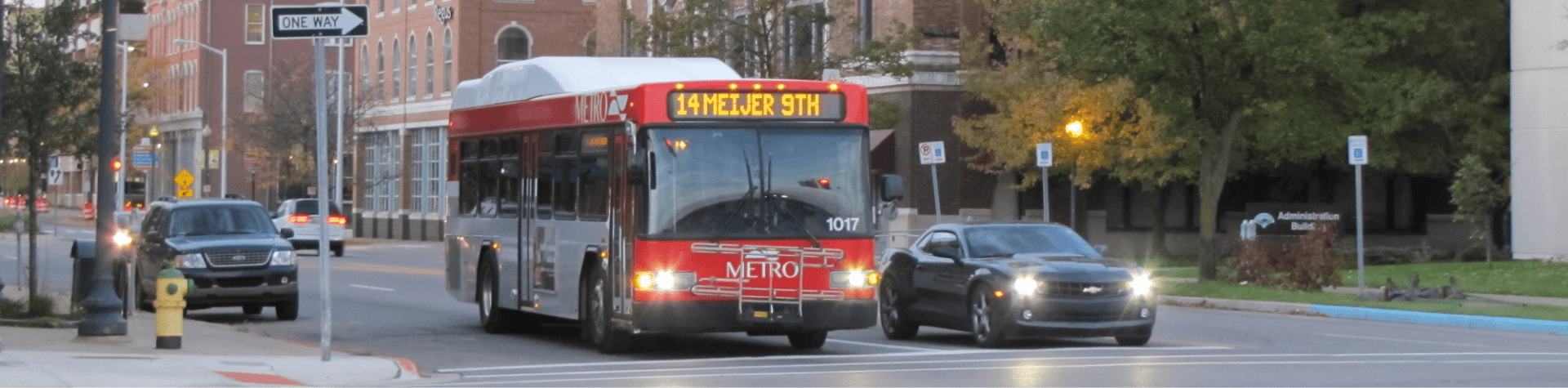 An image of a Kalamazoo Metro bus next to a car at an intersection.